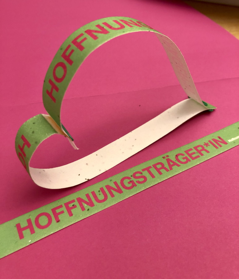 Papierstreifen mit Samen als Armbänder mit Aufschrift "Hoffnungsträger*in"