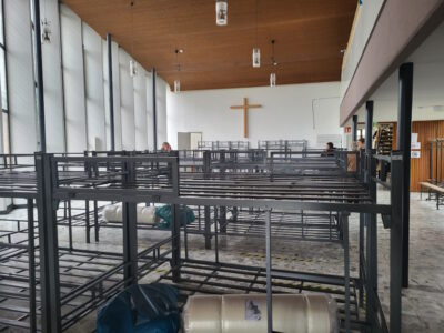 zusammengestellte Betten, im Hintergrund ein Kreuz