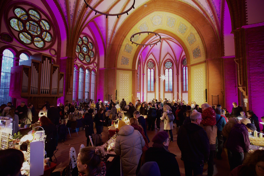 Adventsmarkt im gelb-rosa beleuchteten Kirchenraum der Heilandskirche Leipzig