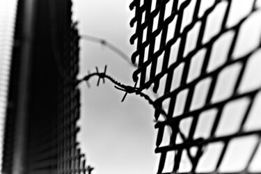 Bild Grenze Feinschwarz Maschendrahtzaun mit Riss und Stacheldraht