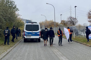 Buchmesse Halle Polizeisicherung vor Messegelände, zwei Personen halten Regenschirme vor Besucher:innen zum Schutz vor kritischen Fotografen