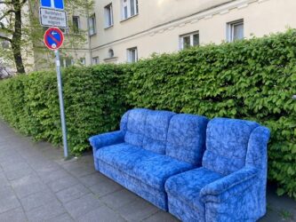 Blaues Sofa Xatnener Str. Blaues Sofa auf dem Gehweg an einer Hecke