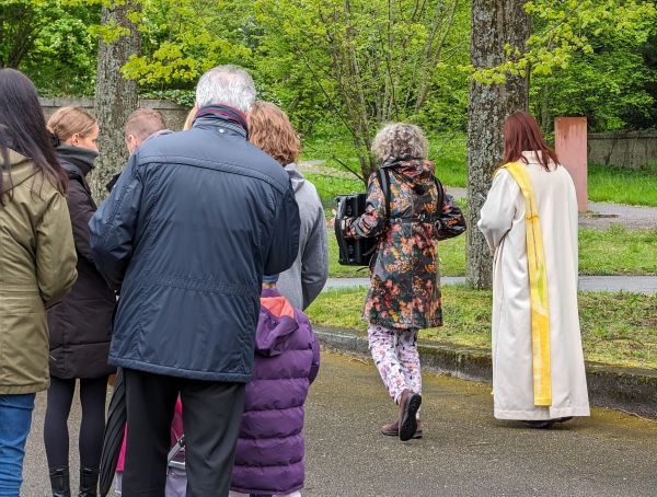 Gruppe mit Liturgin auf Friedhof